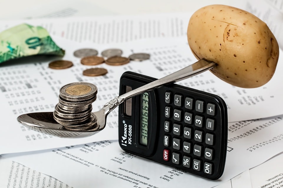 Coins and potato balanced on a spoon and calculator depicting liens