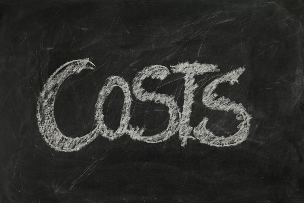 The word "costs" written on chalkboard in capital letters